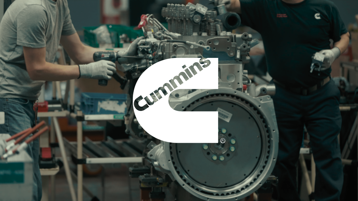 Image of cummins logo overlaid on top manufactruing workers building an engine